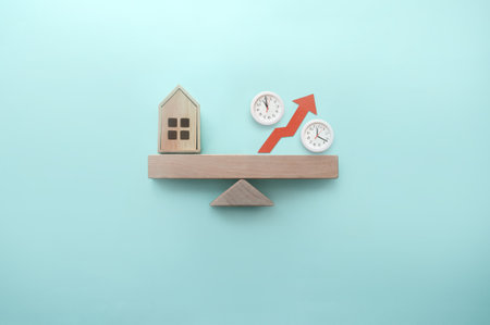 Miniature house and percentage sign with clocks balanced on a seesaw