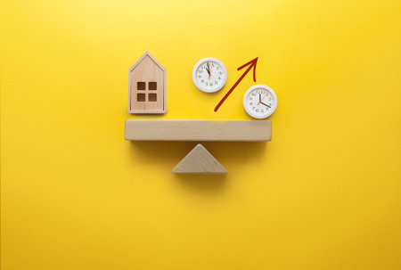 Miniature house and percentage sign with clock faces balanced on a seesaw, investment, mortgage, interest rate decisionの写真素材