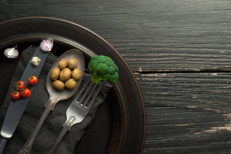 Miniature potatoes, onions and broccoli on cutlery, organic food conceptの写真素材