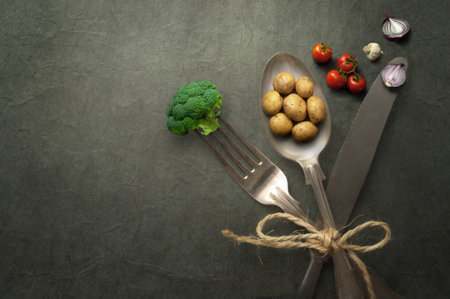 Miniature potatoes, onions and broccoli on cutlery, organic food concept