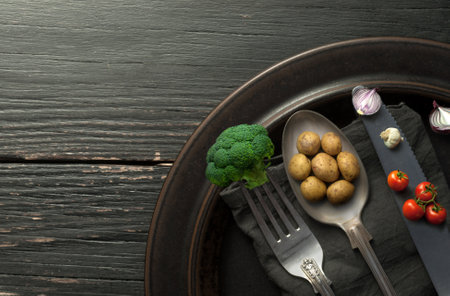 Miniature potatoes, onions and broccoli on cutlery, organic food conceptの写真素材