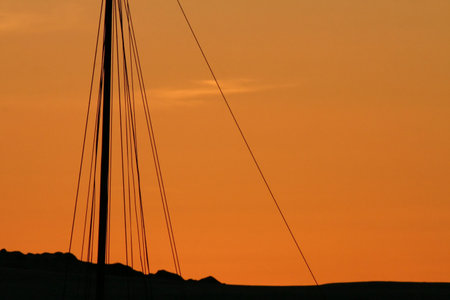 An abstract look at a sailboats mast silhouetted against a sunsetの写真素材