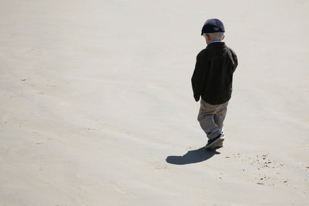 A little boy walking alone on the beachの写真素材