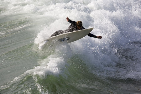A surfer stretches to stay on boardの写真素材