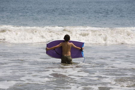 A child new to boogie boarding awaits the next waveの写真素材