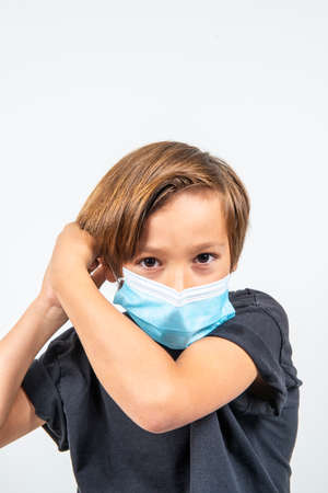 A young boy with a medical mask on a white backgroundの写真素材