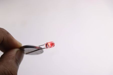 Light bulb connected to coin battery which is glowing red in colorの写真素材