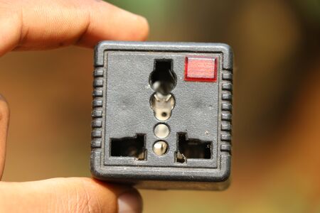 Universal plug adapter held in hand which is used to connect odd type pin plugsの写真素材