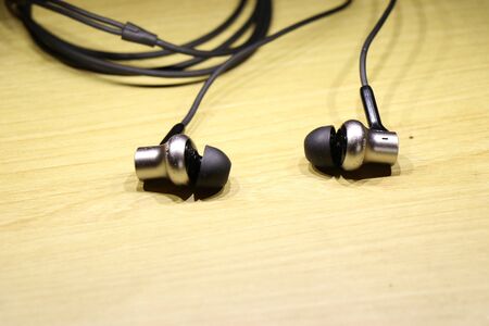 Earphones with shiny silver speaker body on wooden backgroundの写真素材