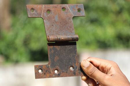 Door hinge used to support door to the frame held in hand which looks rustyの写真素材