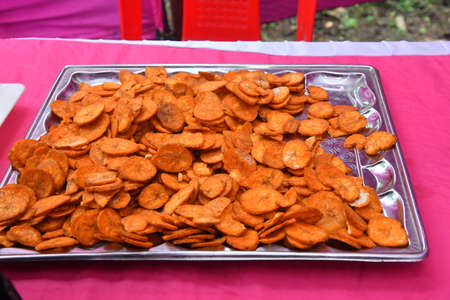 Banana chips snack which is red in color kept on tray for serving