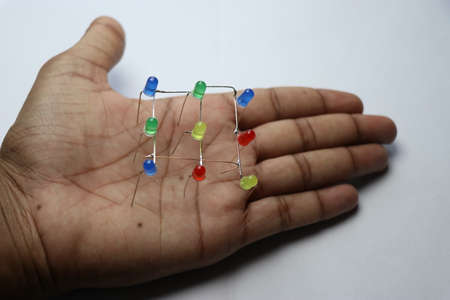 Group of colorful LED diodes connected to form matrix square shape held in hand on white backgroundの写真素材
