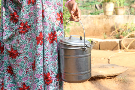 Women holding milk can. Steel milk can being held by women on country sideの写真素材
