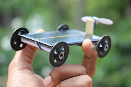 Hand holding solar air car. Car that works on solar energy held in hand on nature background showing...