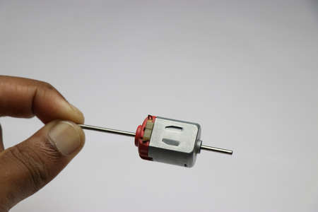 Hand holding one end of shaft from dual shaft dc motor. DC motor for hobby electronics and small...