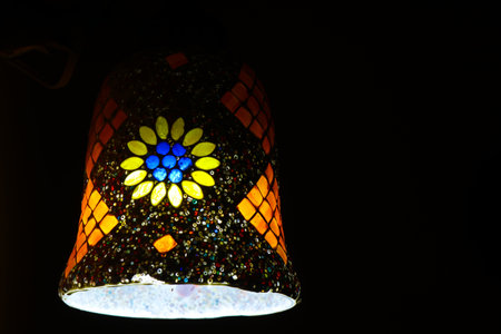 Colorful handmade ceramic lamps hanging in the home illuminate beautiful patterns of lightの写真素材