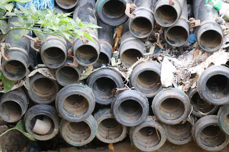 Pipes are stacked in a place that looks old and dirty. PVC pipes used for irrigation purposes...