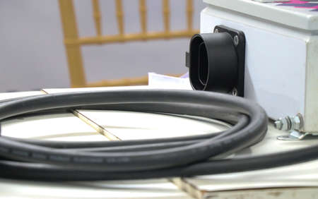 EV charger or electric vehicle charger cord along with its connector board in the background with...
