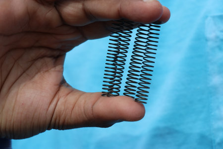 Metal compression springs used to absorb shocks from various load parts held in handの写真素材