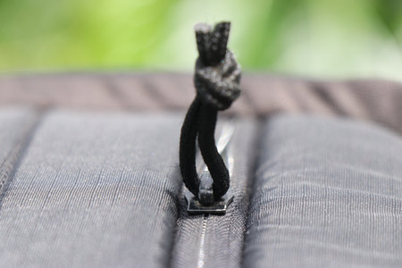 Close up of a zipper from bag with thread piece to open and close the zips
