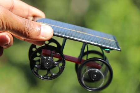 Solar powered working model car held in hand with 3D printed wheels and a natural background