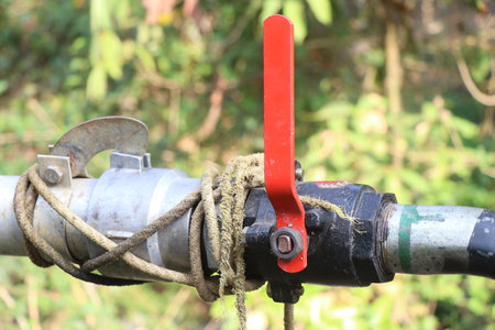 heavy duty water shutoff valve installed on a water carrying pipe. Ball valve threaded with red...