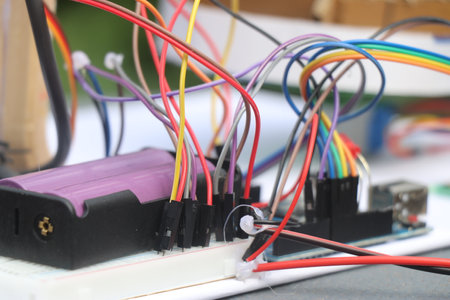 Set of jumper cables connected to micro controller and breadboard with a battery as part of electronics project prototypingの写真素材