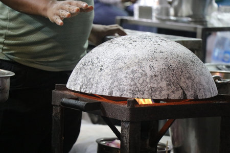 Smooth cast iron tawa placed over a gas stove to cook some roti by the side of food streetの写真素材