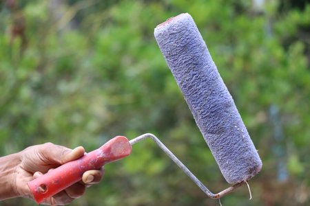 Used paint roller machine used to paint flat surfaces like walls held on the hand on outdoors