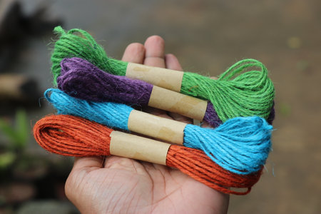 Holding a group of multicolored jute thread twine. Colored jute rope for hobby and craftsの写真素材