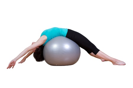 Beautiful young and athletic woman leaning backwards over a fitness ball - on whiteの写真素材