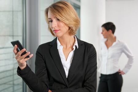 Business woman using phone and colleagueの写真素材