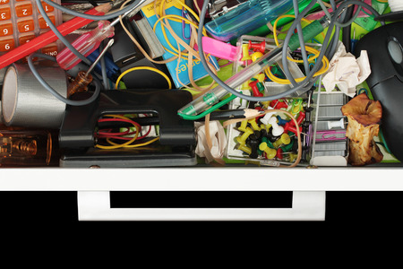 Elevated view of the seedy world of the untidy stationery drawer isolated on black with copy spaceの写真素材