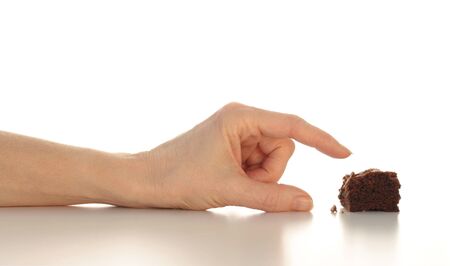 Arm with hand reaching for the last piece of chocolate brownie, top half isolated on whiteの写真素材