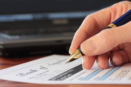 Hand with pen completing a form bank  form are fictitious  created by photographer