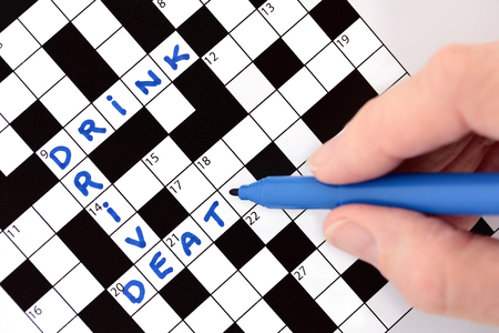 Hand completing crossword with Drink Drive Death messageの写真素材