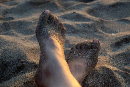 Feet with sand at the beach at sunsetの写真素材