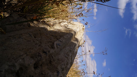 Low-angle view of a stone pillar against a blue sky with clouds.の写真素材