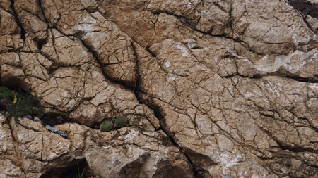An extreme close up of a dry, cracked surface composed of earth, clay, and rock fragments, creating a rugged, abstract pattern.の写真素材