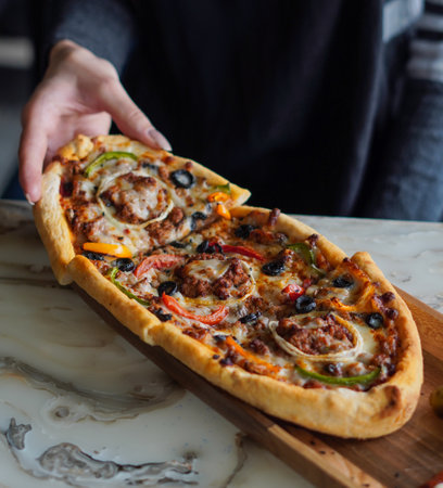Pizza with various toppings on a wooden board in a restaurantの写真素材