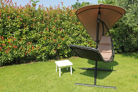 Garden chair and table in the garden with green grass and flowersの写真素材