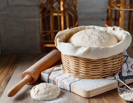 Basket with raw dough and rolling pin on a wooden background.の素材