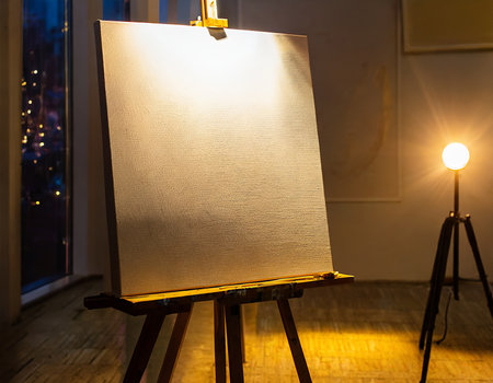 Photo of a canvas on a tripod in the light of a lampの素材