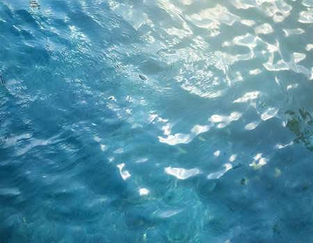 Blue water surface with ripples and sun reflections. Abstract background.の素材