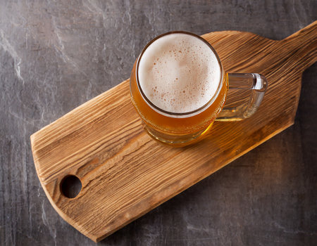 Mug of beer on a wooden board on a dark background.の素材