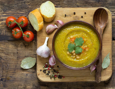 Vegetable soup with chickpeas, tomatoes and garlic on a wooden backgroundの素材