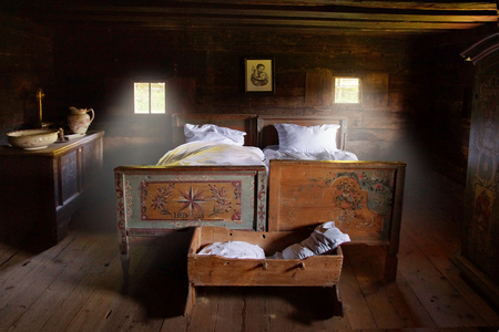 Old marriage bed, cradle, jug and bowl in a bedroom of a farmhouse.の写真素材