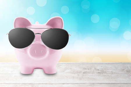 Summer piggy bank with sunglasses on the beachの写真素材