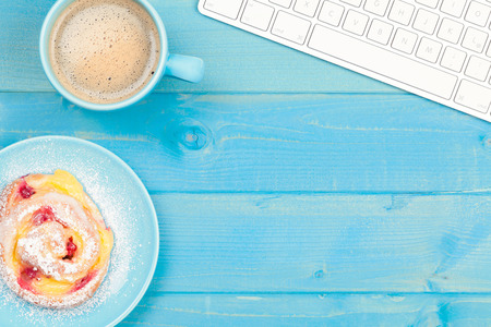 Coffee cup with a cake on a blue wooden table. Business background.の写真素材