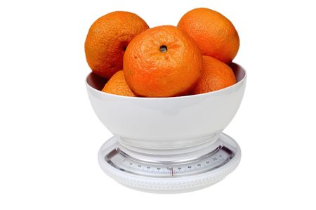 Tangerines on kitchen weight over whiteの写真素材